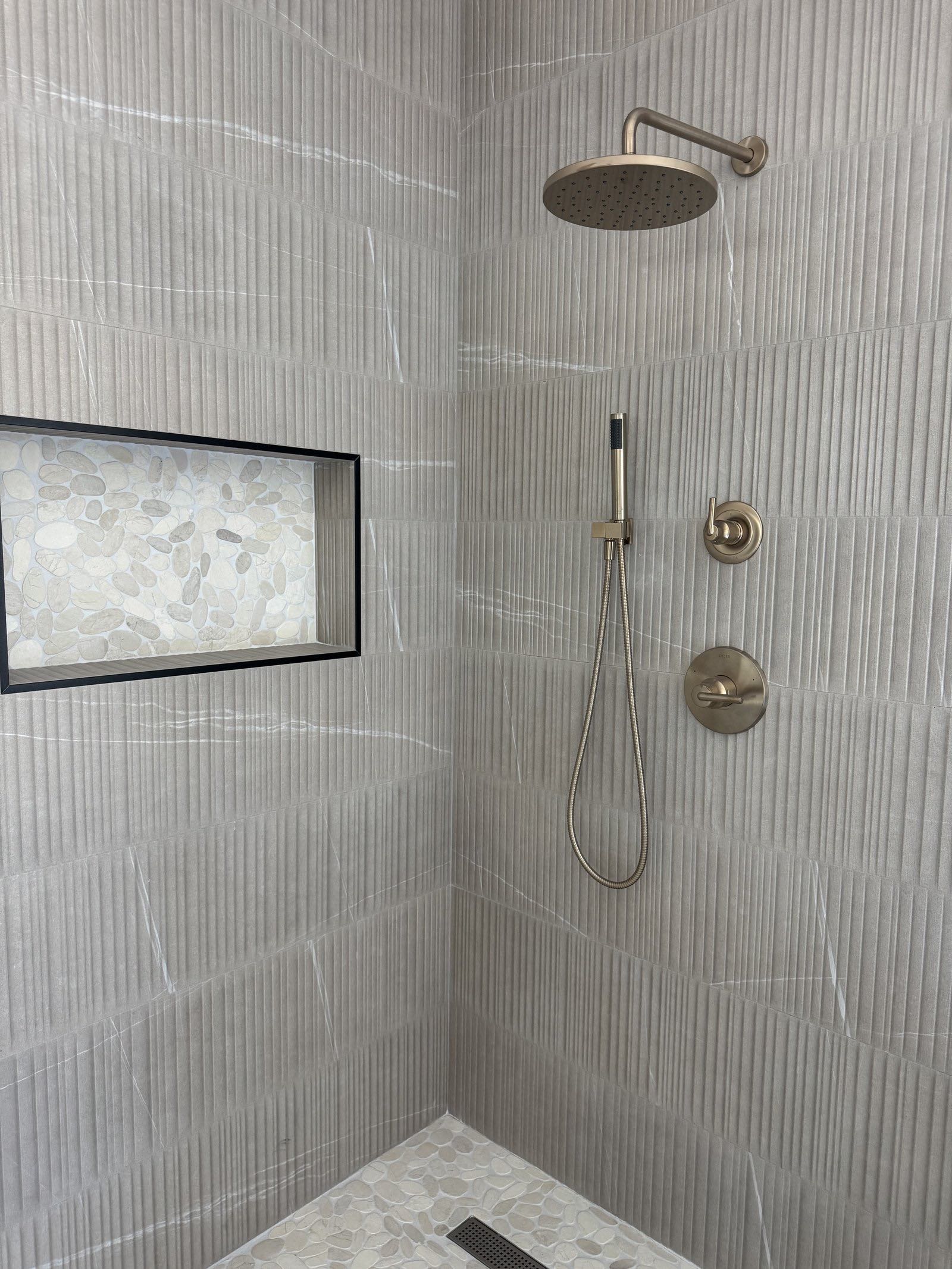 Shower niche with pebble tile accent and black metal trim