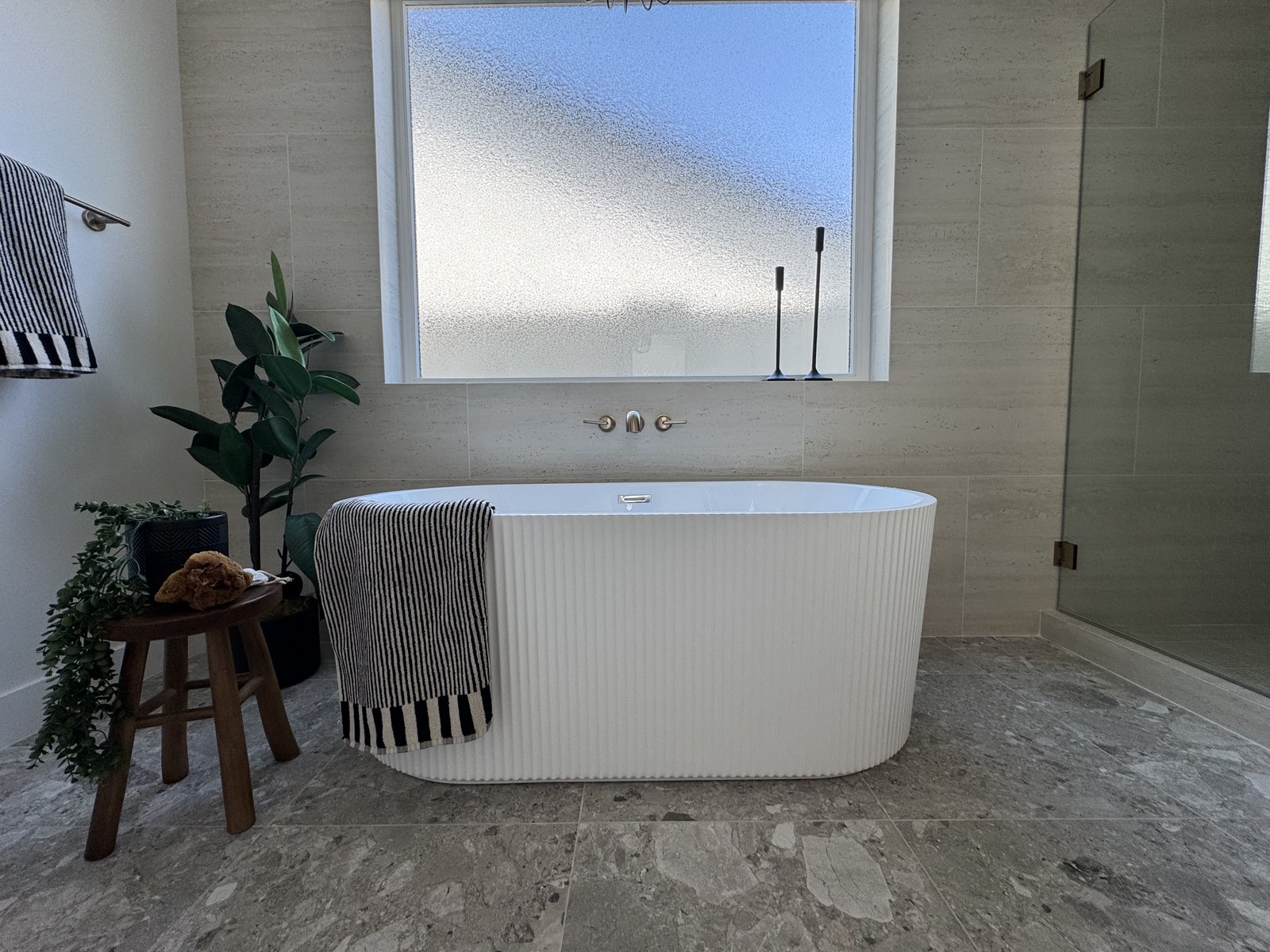Mesa AZ bathroom remodel with fluted sculptural freestanding tub, travertine paver floor, frosted clerestory window, and neutral palette