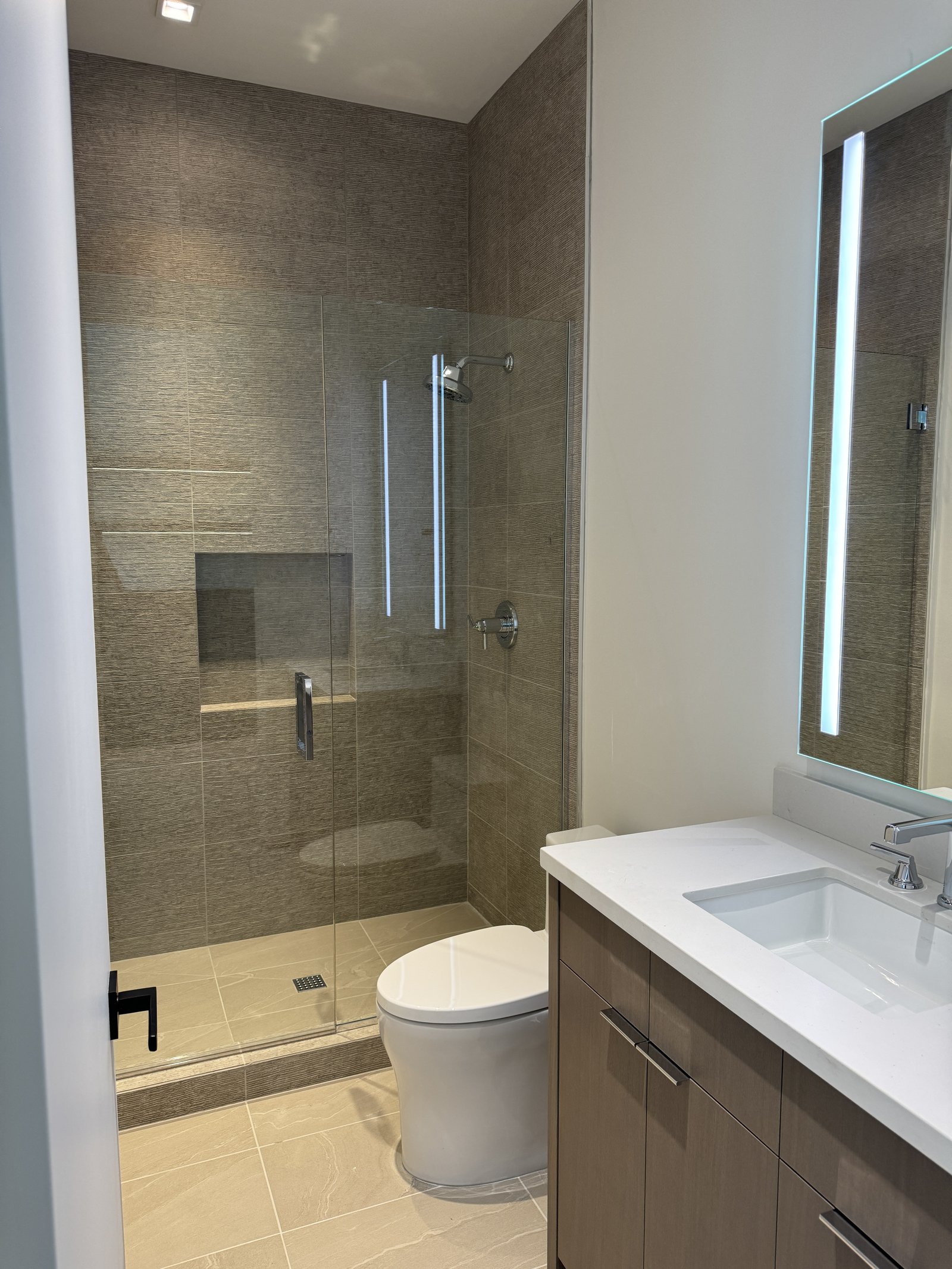 Queen Creek AZ guest bathroom with textured large-format porcelain tile shower, dark wood vanity, and white quartz counter
