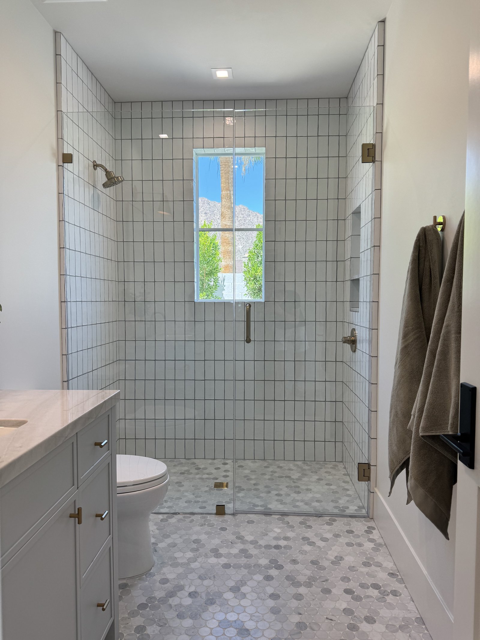 Tempe AZ bathroom remodel with white grid tile shower, dark grout, hex marble floor, frameless glass enclosure, and gray shaker vanity