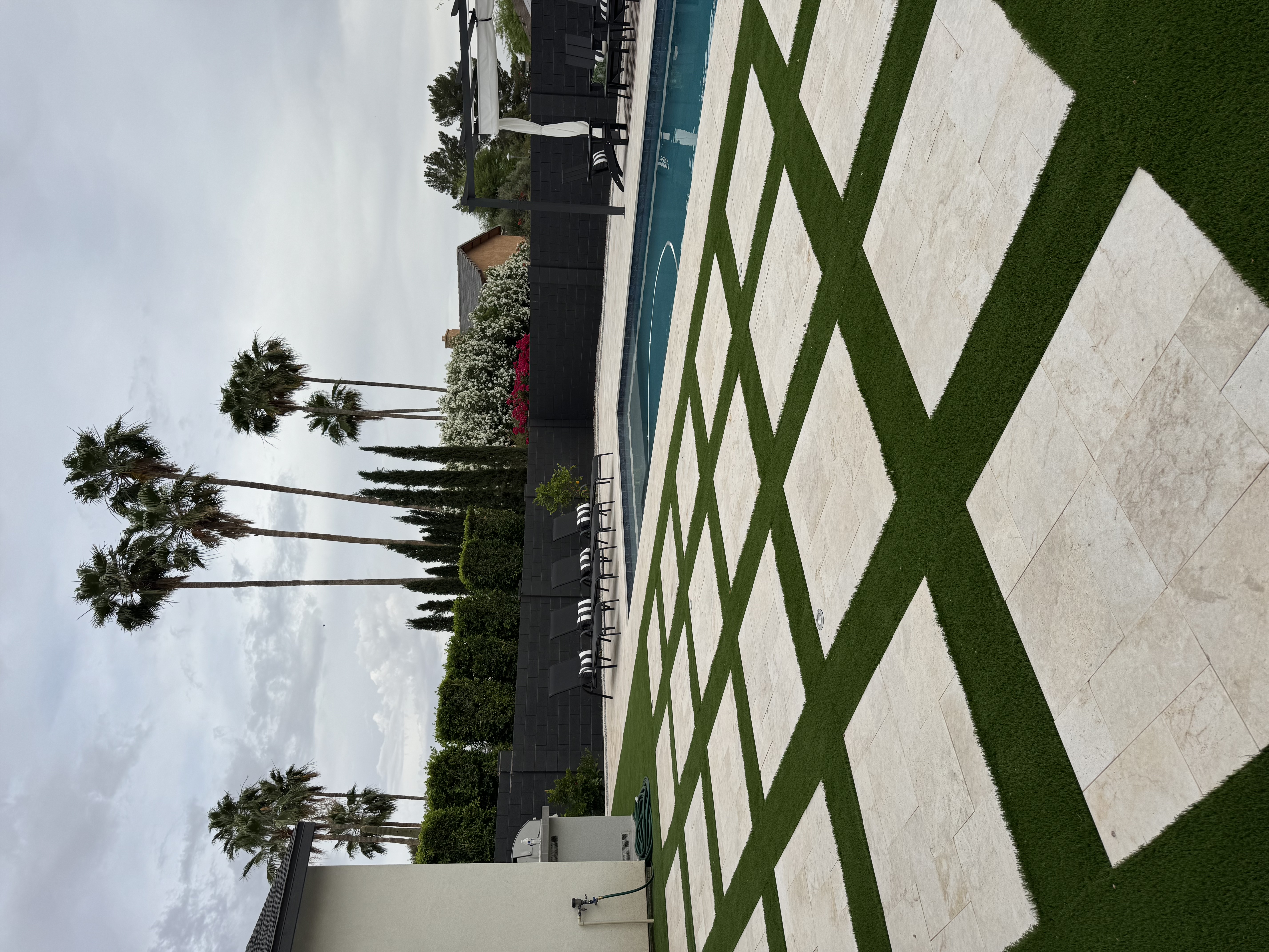 Resort-style Scottsdale backyard with synthetic turf, travertine pavers, and outdoor living area