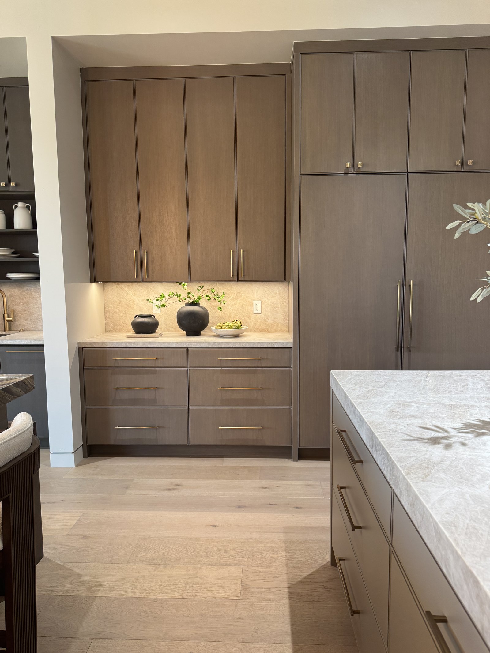 Phoenix AZ kitchen remodel with mid-tone wood cabinetry, dramatic veined quartzite countertops, Wolf range, and brass faucet